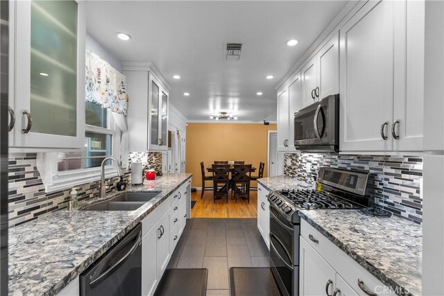 kitchen with stainless steel appliances, sink, decorative backsplash, and white cabinets