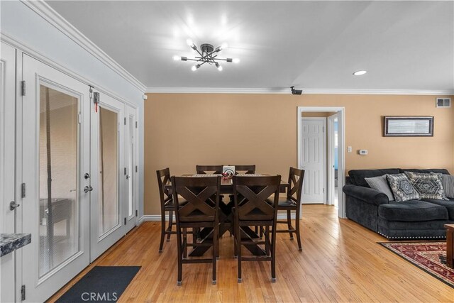 dining area featuring a notable chandelier, ornamental molding, and light wood-type flooring