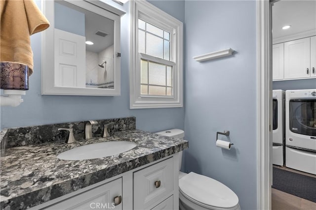 bathroom featuring vanity, washing machine and dryer, and toilet