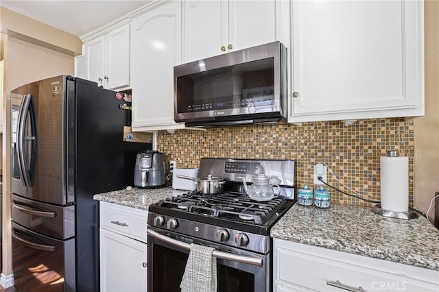 kitchen with light stone countertops, appliances with stainless steel finishes, white cabinets, and backsplash