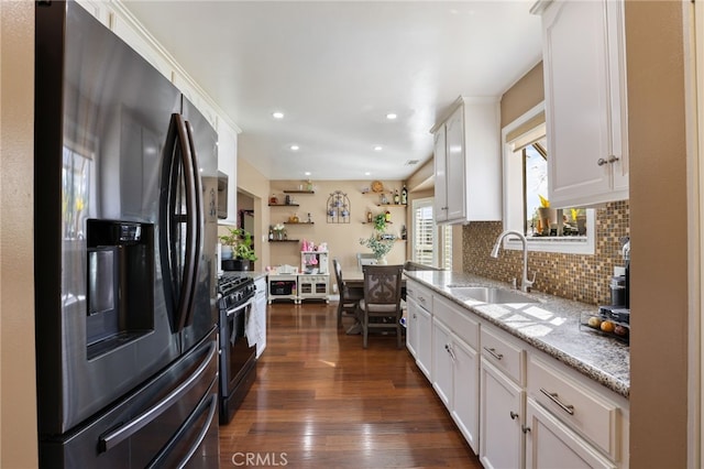 kitchen featuring white cabinetry, sink, black gas stove, stainless steel fridge with ice dispenser, and light stone countertops