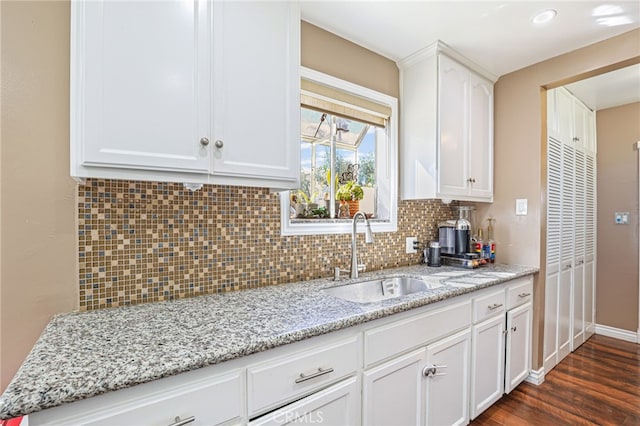 kitchen featuring dark wood-type flooring, sink, white cabinetry, tasteful backsplash, and light stone counters