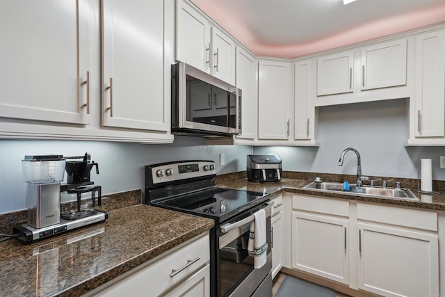 kitchen with sink, dark stone counters, white cabinets, and appliances with stainless steel finishes