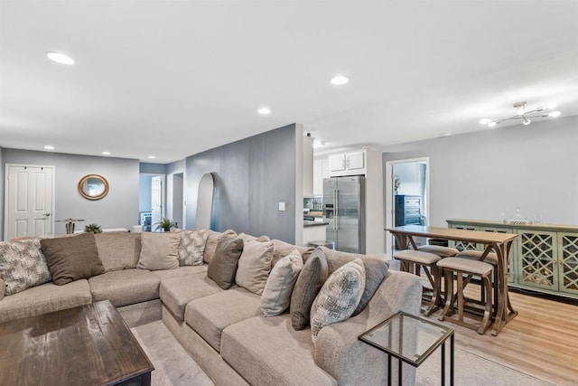 living room with light wood-style flooring, arched walkways, and recessed lighting