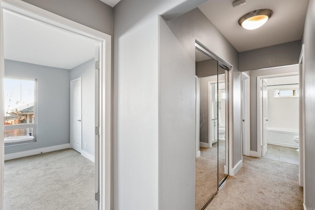 corridor with baseboards and carpet flooring