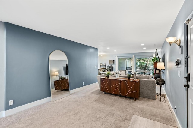 living room featuring arched walkways, light colored carpet, baseboards, and recessed lighting