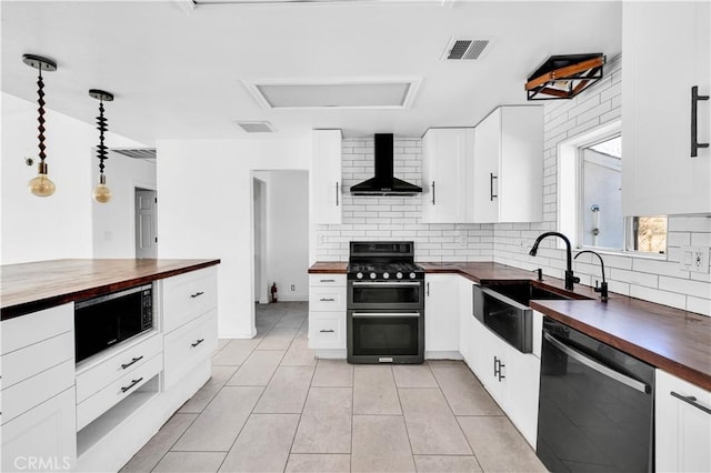 kitchen with wall chimney exhaust hood, sink, wooden counters, hanging light fixtures, and black appliances