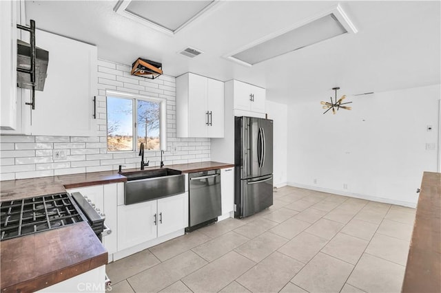 kitchen featuring white cabinetry, appliances with stainless steel finishes, butcher block counters, and sink