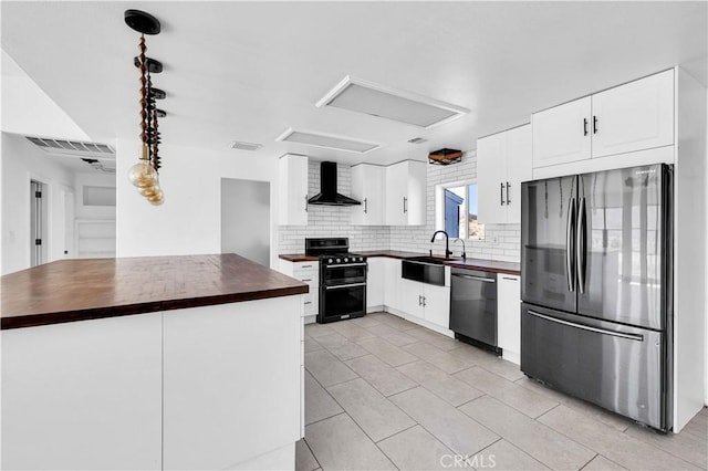 kitchen with wall chimney exhaust hood, sink, butcher block countertops, white cabinetry, and appliances with stainless steel finishes