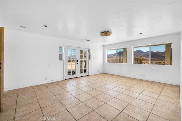 empty room featuring french doors and light tile patterned flooring