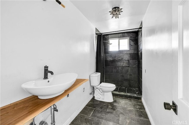 bathroom featuring sink, tiled shower, and toilet