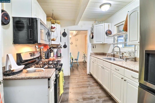 kitchen with appliances with stainless steel finishes, beam ceiling, sink, and white cabinets