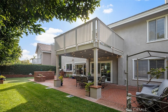 back of property featuring a patio, outdoor lounge area, a yard, and a balcony