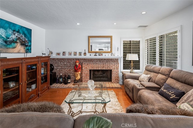 living room featuring a fireplace, wood-type flooring, and a textured ceiling