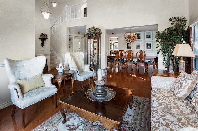 living room with hardwood / wood-style flooring, a towering ceiling, and an inviting chandelier