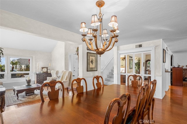 dining space with hardwood / wood-style flooring, a textured ceiling, and an inviting chandelier