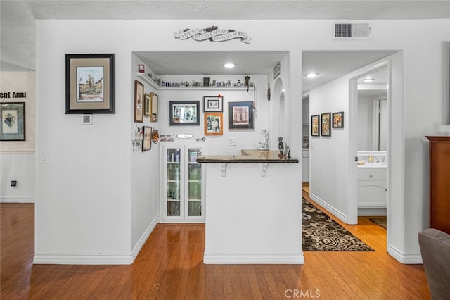 bar with white cabinetry, wood-type flooring, and sink