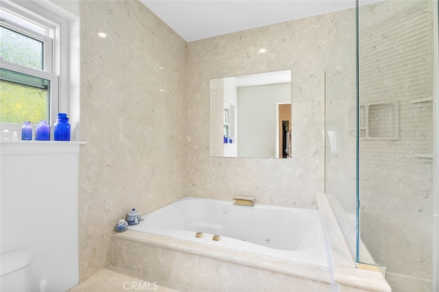 bathroom featuring tiled bath and toilet