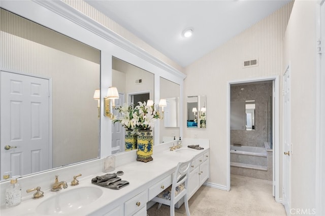 bathroom with vaulted ceiling, tiled bath, and vanity