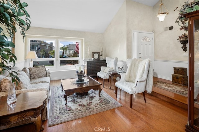 sitting room with hardwood / wood-style floors and high vaulted ceiling