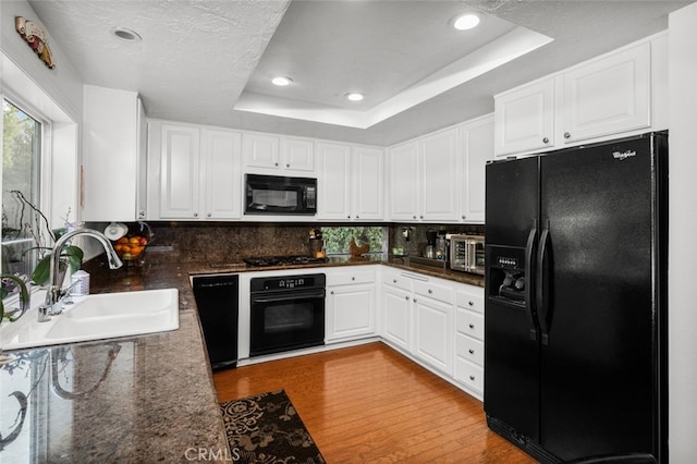 kitchen with sink, black appliances, a raised ceiling, light hardwood / wood-style floors, and white cabinets