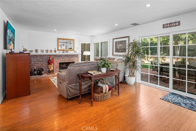 living room with hardwood / wood-style floors, a textured ceiling, and a fireplace