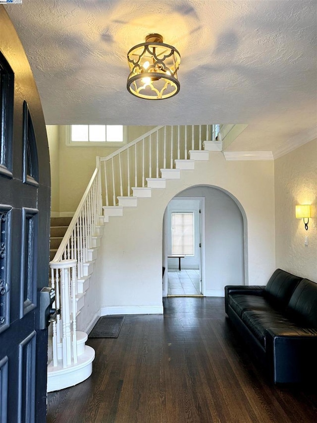 foyer entrance featuring hardwood / wood-style flooring, ornamental molding, and a textured ceiling