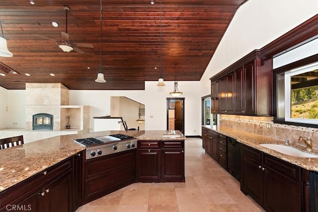 kitchen featuring hanging light fixtures, wooden ceiling, a tile fireplace, stainless steel gas stovetop, and decorative backsplash