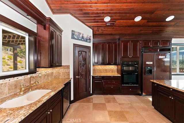 kitchen featuring paneled fridge, sink, black double oven, wood ceiling, and light stone countertops