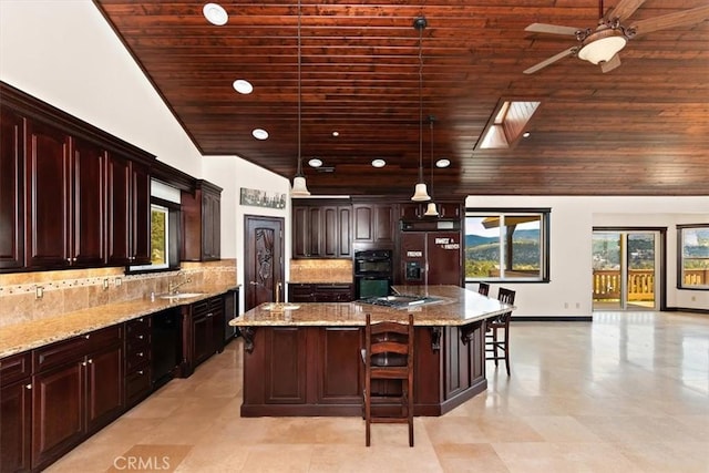 kitchen featuring light stone counters, hanging light fixtures, paneled built in refrigerator, a kitchen breakfast bar, and a kitchen island