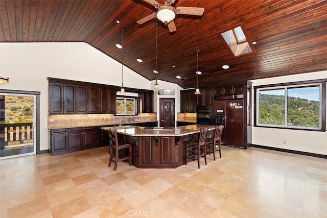 kitchen featuring light stone counters, paneled refrigerator with ice dispenser, hanging light fixtures, a kitchen island, and decorative backsplash