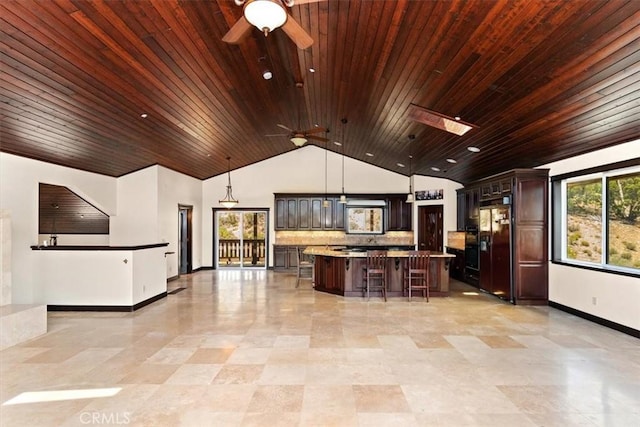 kitchen with a breakfast bar, dark brown cabinets, refrigerator with ice dispenser, a kitchen island, and pendant lighting