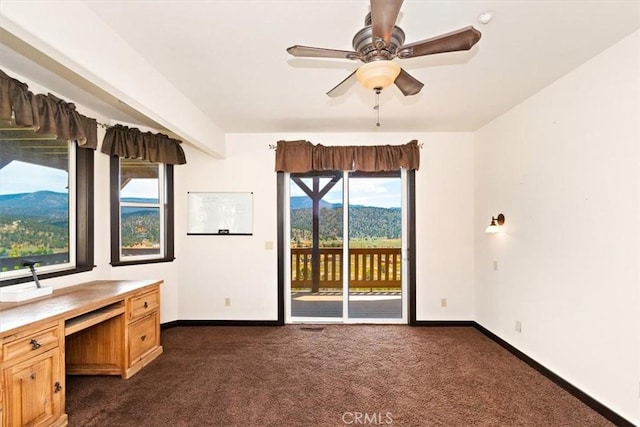 unfurnished office featuring ceiling fan and dark colored carpet