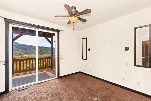 unfurnished room featuring a mountain view and carpet