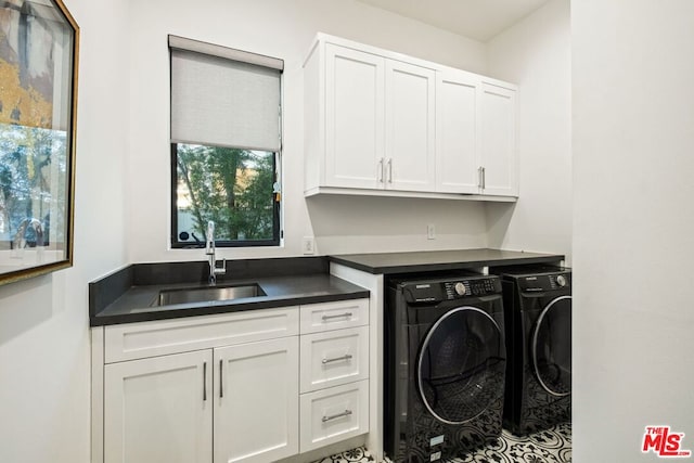 clothes washing area with separate washer and dryer, sink, and cabinets