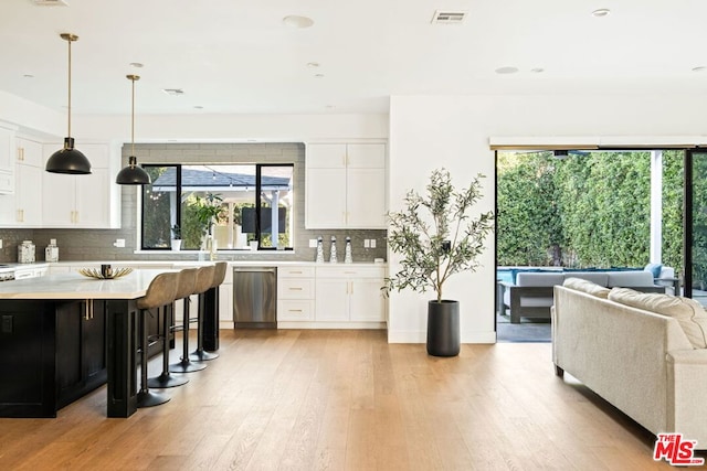 kitchen featuring white cabinetry, pendant lighting, stainless steel dishwasher, and a healthy amount of sunlight