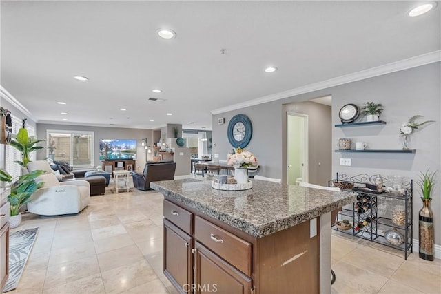 kitchen featuring light tile patterned flooring, ornamental molding, a kitchen island, and dark stone counters