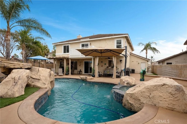 rear view of house with a balcony, a patio, pool water feature, and a pool with hot tub