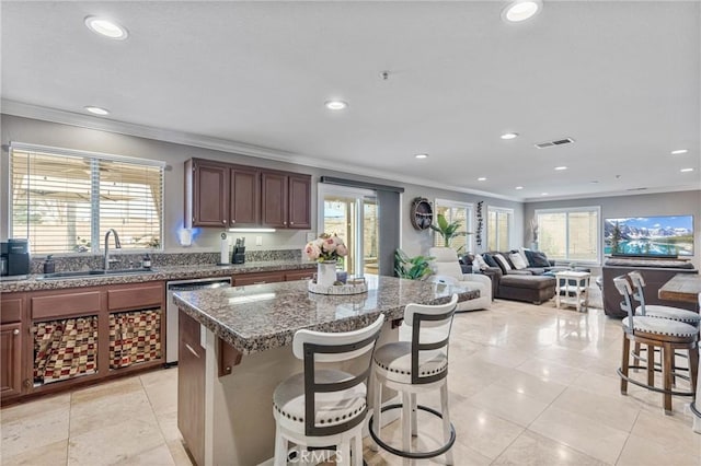 kitchen with sink, a breakfast bar, dishwasher, plenty of natural light, and a center island