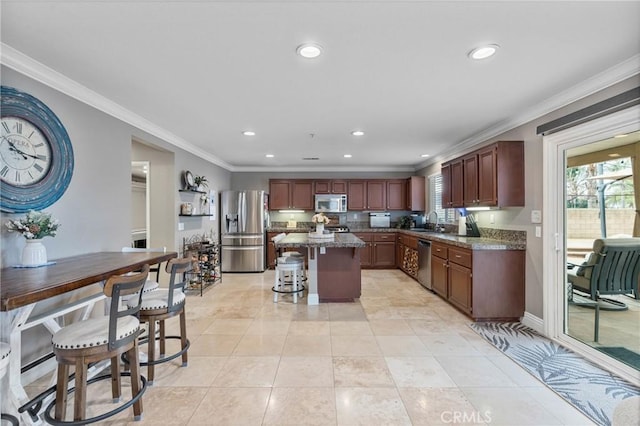 kitchen with sink, stone countertops, appliances with stainless steel finishes, a kitchen island, and a healthy amount of sunlight