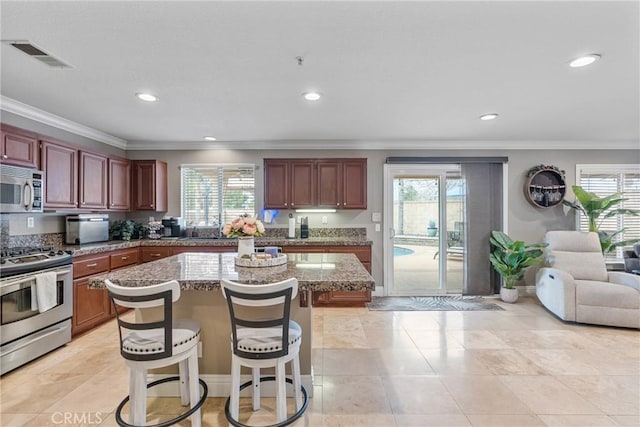 kitchen with a wealth of natural light, stainless steel appliances, a breakfast bar, and a kitchen island