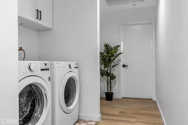 laundry area featuring cabinets, light hardwood / wood-style floors, and washer and dryer