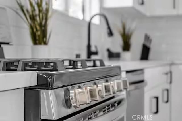 details with gas stove and white cabinets