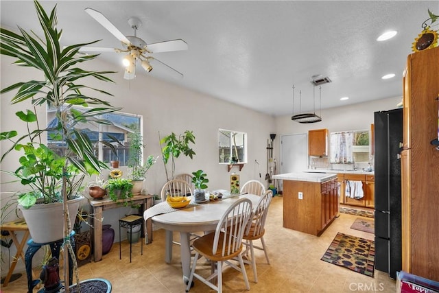 kitchen featuring light tile patterned floors, ceiling fan, backsplash, a center island, and black fridge