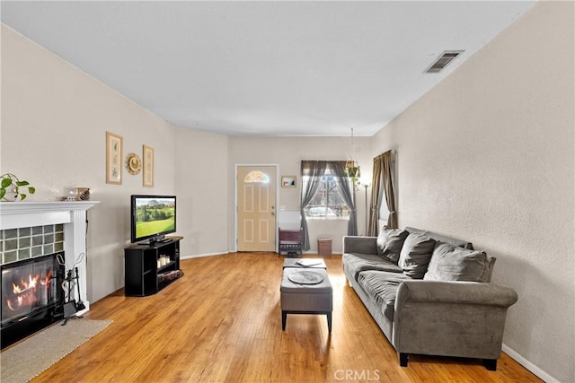 living room with light hardwood / wood-style floors and a tile fireplace