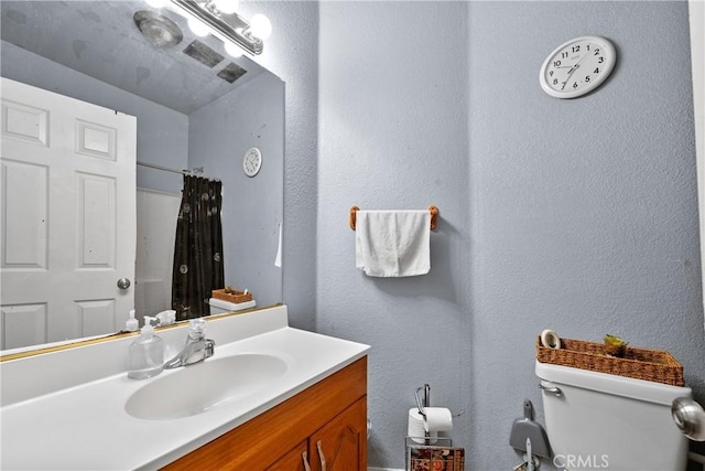 bathroom featuring walk in shower, vanity, and toilet