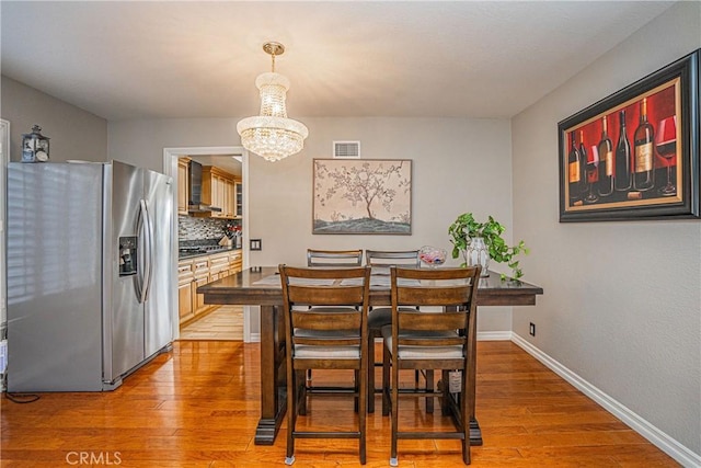 dining space with wood-type flooring and a chandelier