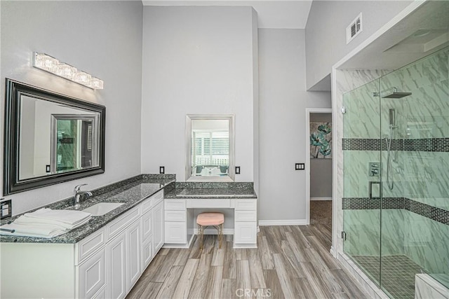 bathroom with vanity, an enclosed shower, hardwood / wood-style flooring, and a high ceiling