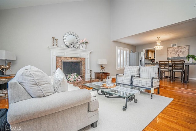 living room featuring hardwood / wood-style flooring, a fireplace, and a notable chandelier