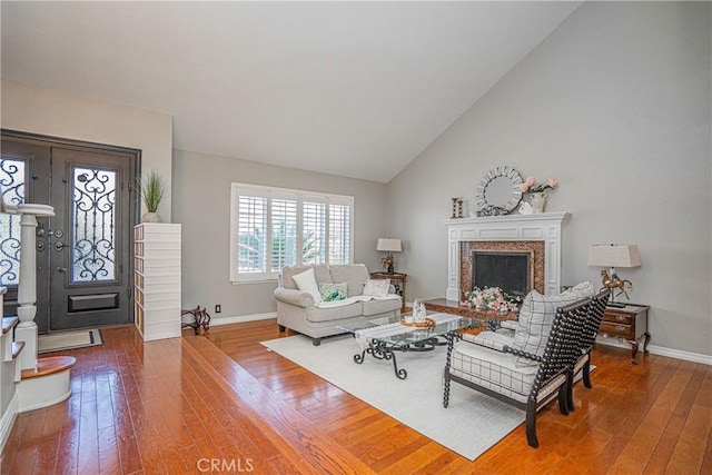 living room with hardwood / wood-style flooring, a premium fireplace, and high vaulted ceiling